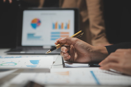 Financial analysts analyze business financial reports on a digital tablet planning investment project during a discussion at a meeting of corporate showing the results of their successful teamwork.の写真素材