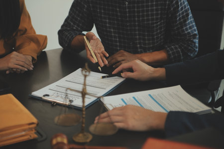 Justice and Law concept. Legal counsel presents to the client a signed contract with gavel and legal law or legal having team meeting at law firm in backgroundの写真素材