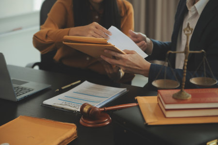 Justice and Law concept. Legal counsel presents to the client a signed contract with gavel and legal law or legal having team meeting at law firm in backgroundの写真素材