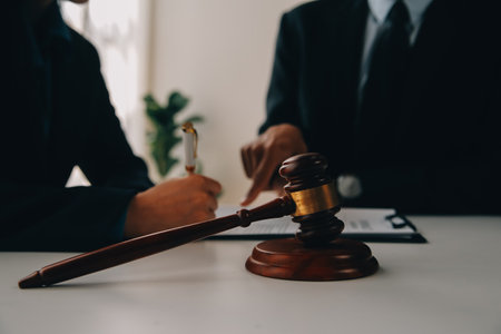 Justice and Law concept. Legal counsel presents to the client a signed contract with gavel and legal law or legal having team meeting at law firm in backgroundの写真素材