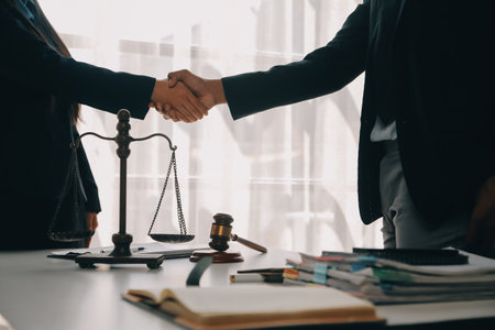 Justice and Law concept. Legal counsel presents to the client a signed contract with gavel and legal law or legal having team meeting at law firm in backgroundの写真素材
