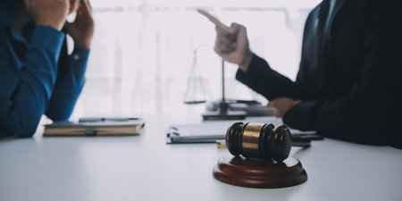 Justice and Law concept. Legal counsel presents to the client a signed contract with gavel and legal law or legal having team meeting at law firm in backgroundの写真素材