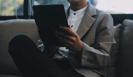 Happy businessman dressed in suit in modern office using tabletの写真素材