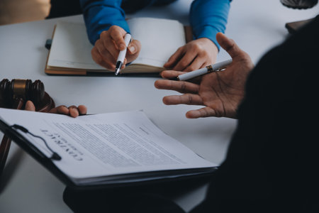 Justice and Law concept. Legal counsel presents to the client a signed contract with gavel and legal law or legal having team meeting at law firm in backgroundの写真素材