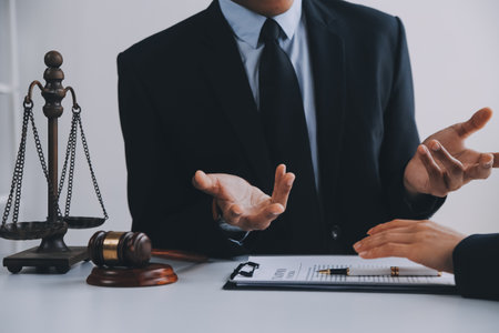 Justice and Law concept. Legal counsel presents to the client a signed contract with gavel and legal law or legal having team meeting at law firm in backgroundの写真素材