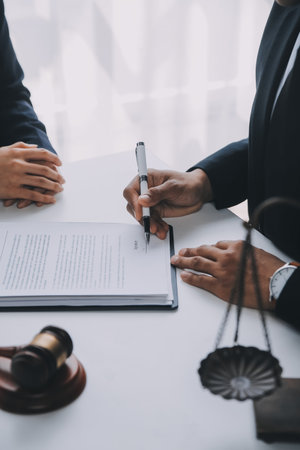 Justice and Law concept. Legal counsel presents to the client a signed contract with gavel and legal law or legal having team meeting at law firm in backgroundの写真素材