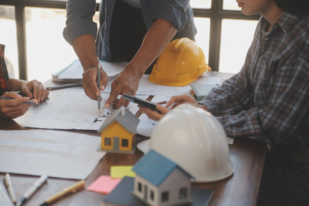 A team of construction engineers talks to managers and construction workers at the construction site. Quality inspection, work plan, home and industrial building design projectの写真素材