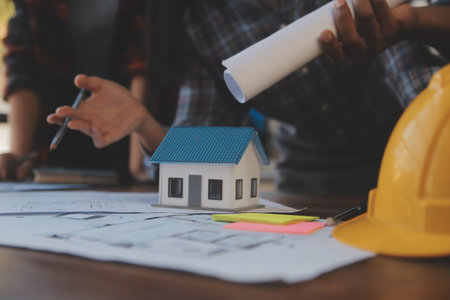 A team of construction engineers talks to managers and construction workers at the construction site. Quality inspection, work plan, home and industrial building design projectの写真素材