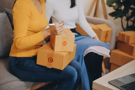 Asian SME business women use laptop computer checking customer order online shipping boxes at home. Starting Small business entrepreneur SME freelance. Online business, Work at home concept.の写真素材