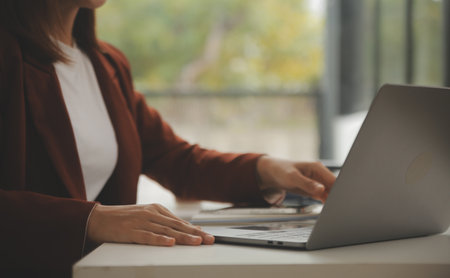 Shot of a asian young business Female working on laptop in her workstation.の写真素材
