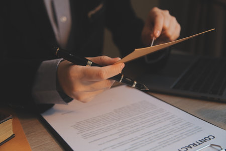 Business and lawyers discussing contract papers with brass scale on desk in office. Law, legal services, advice, justice and law concept picture with film grain effectの写真素材