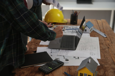 Engineers are consulting the team to design an architectural structure for clients with blueprints and building models to work at office.の写真素材