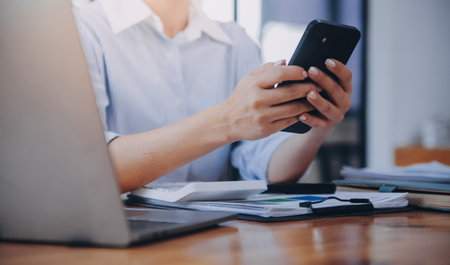 Portrait of a happy Asian businesswoman using mobile phone indoor, Asian businesswoman working in modern office.の写真素材