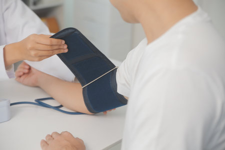 Male doctor uses a blood pressure monitor to check the body pressure and pulse of the patients who come to the hospital for check-ups, Medical treatment and health care concept.の写真素材