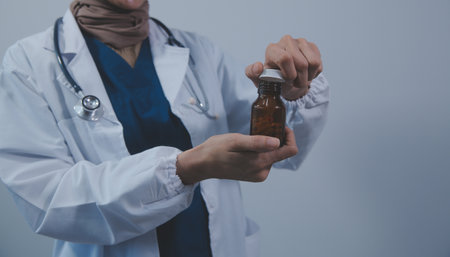 Southeast Asian medical doctor holding a bottle of pills, smiling isolated white backgroundの写真素材