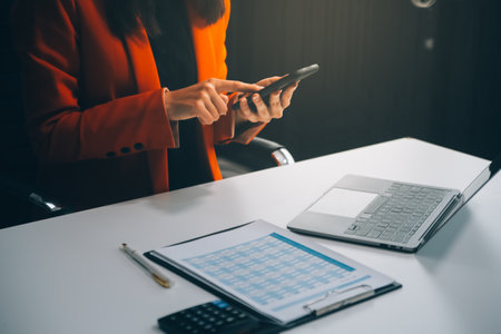 Businessman working at office with calculator documents phone laptop on desk, Asian woman doing planning analyzing the financial report, business plan investment, finance analysis conceptの写真素材