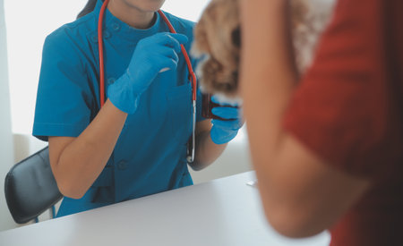 Closeup shot of veterinarian hands checking dog by stethoscope in vet clinicの写真素材