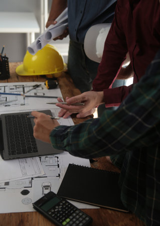 Engineers are consulting the team to design an architectural structure for clients with blueprints...