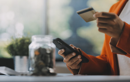 Woman is doing online purchases. Girl is doing shopping using phone and credit card at home.の写真素材
