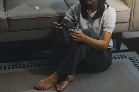 Upset woman frustrated by problem with work or relationships, sitting on couch, embracing knees, covered face in hand, feeling despair and anxiety, loneliness, having psychological troubleの写真素材