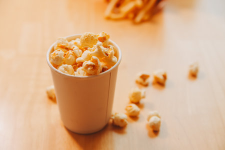 A bucket of popcorn, top-view, warm colors, light brown wooden background, flat lay, daylight macro close-upの写真素材