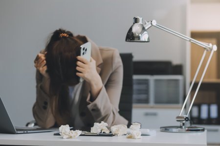 Asian women sitting in an office With stress and eye strain Tired, portrait of sad unhappy tired frustrated disappointed lady suffering from migraine sitting at the table, Sick worker conceptの写真素材