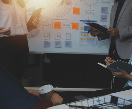 Financial analysts analyze business financial reports on a digital tablet planning investment project during a discussion at a meeting of corporate showing the results of their successful teamwork.の写真素材