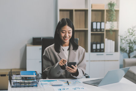Happiness Entrepreneur beautiful business asian young woman wear casual use mobile phone for shopping online enjoy with social media and laptop at home.Small Business Startup.online bankingの写真素材