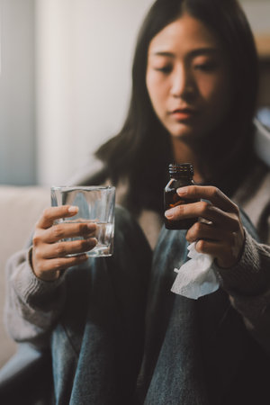 Upset woman frustrated by problem with work or relationships, sitting on couch, embracing knees, covered face in hand, feeling despair and anxiety, loneliness, having psychological troubleの写真素材