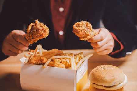 close up focus woman hand hold fried chicken for eat,girl with fast food conceptの写真素材