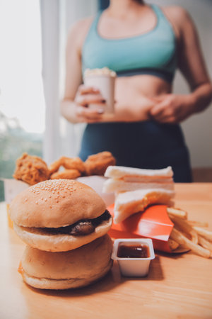 To eat or not. Cheerless plump woman looking at the burger while thinking to eat it or notの写真素材