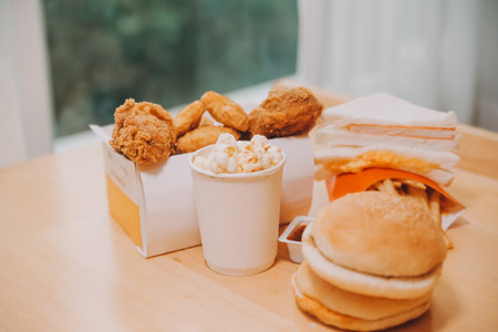 fast food, people and unhealthy eating concept - close up of woman hands holding hamburger or cheeseburgerの写真素材