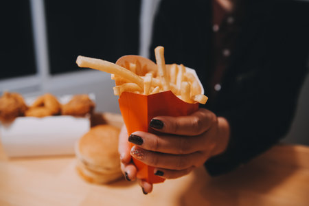 Asian woman holding french fries and eating happily in restaurantの写真素材