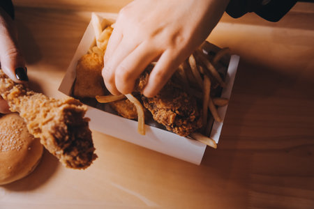 close up focus woman hand hold fried chicken for eat,girl with fast food conceptの写真素材