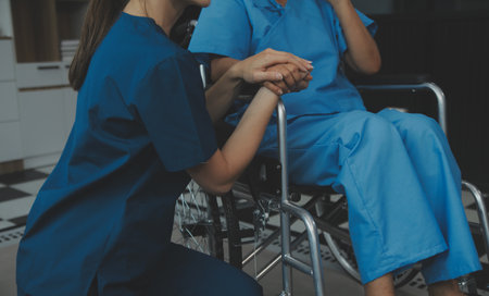 Doctor giving hope. Close up shot of young female physician leaning forward to smiling elderly lady patient holding her hand in palms. Woman caretaker in white coat supporting encouraging old personの写真素材