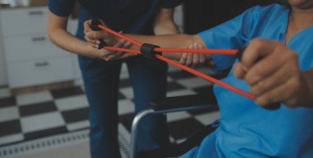 Personal trainer assisting senior woman with resistance band. Rehabilitation physiotherapy worker...
