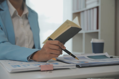 Charming Young asian businesswoman sitting on laptop computer in the office, making report calculating balance Internal Revenue Service checking document.の写真素材