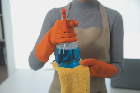 Woman cleaning table using rag and diffuser at home.