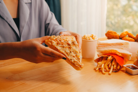 Cropped image of woman holding pizza slice at restaurant
