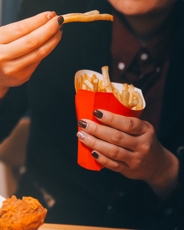 Asian woman holding french fries and eating happily in restaurantの写真素材