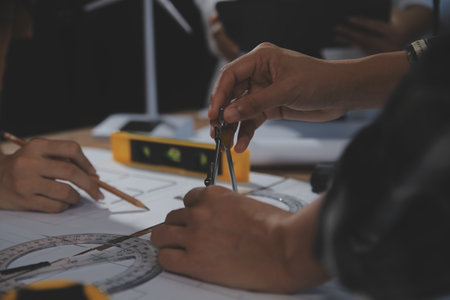 Team of multiethnic architects working on construction plans in meeting room. Engineers discussing on project in office. Mature businessman and woman standing around table working on blueprint.の写真素材