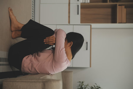 Depressed woman sitting alone on the bed with hands on head feel stress, sad and worried in the dark bedroom and low light environmentの写真素材