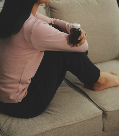Depressed woman sitting alone on the bed with hands on head feel stress, sad and worried in the dark bedroom and low light environmentの写真素材