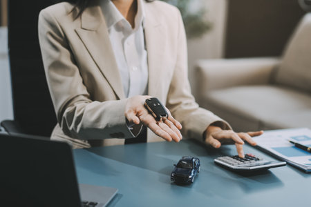 Business car rental company service, Close up hand of agent dealer giving, holding car key to customer renter, new owner after signed rental, purchase contract in document, vehicle sales agreement.の写真素材