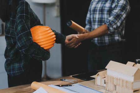 Architect and construction engineer holding hands while working for teamwork and cooperation concept after completing an agreement at construction site, office, close-up imageの写真素材