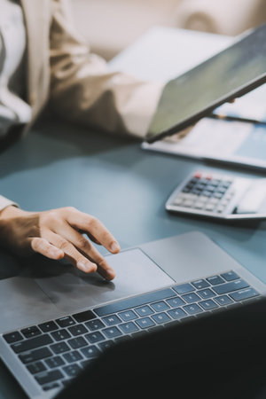 Asian Businesswoman Using laptop computer and working at office with calculator document on desk,...