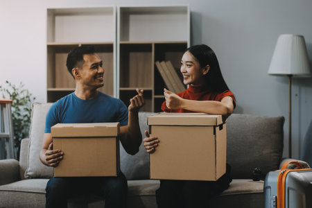 Young couple with big boxes moving into a new house, new apartment for couple, young man and woman helping to lift boxes and organize things for the new home, Moving house.の写真素材