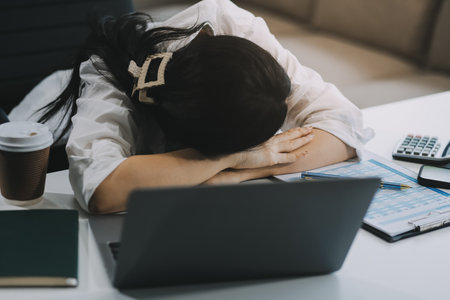 Asian women are stressed while working on laptop, Tired asian businesswoman with headache at office, feeling sick at work, copy spaceの写真素材