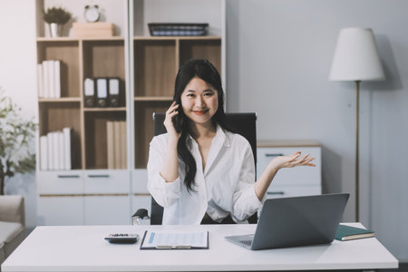 Attractive asian woman using a laptop PC and a smart phone.の写真素材