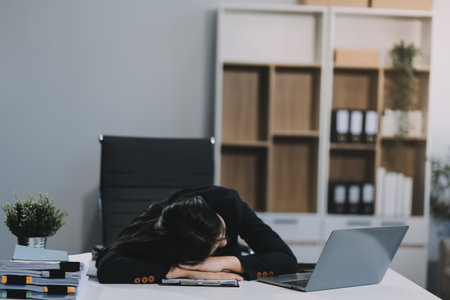 Tired businesswoman sleeping on the desk, in front of the computer screen.の写真素材
